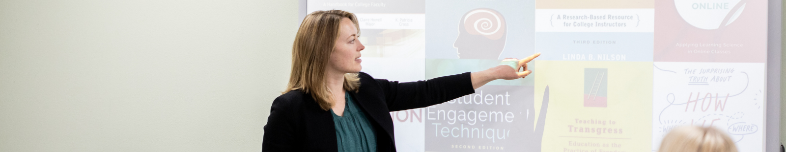 A woman points at a powerpoint display on a board